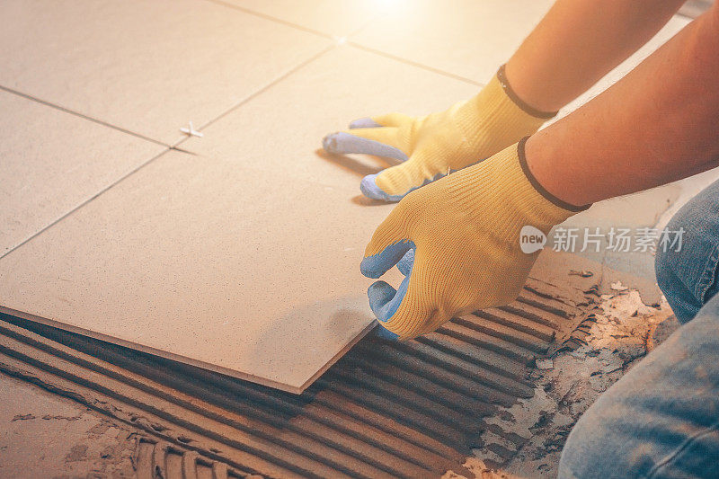 瓷砖用有缺口的抹刀涂胶水把瓷砖粘在地板上