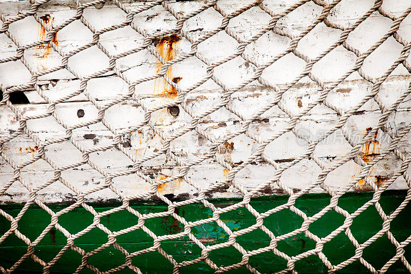 渔网在旧的绿色和白色油漆船板背景。