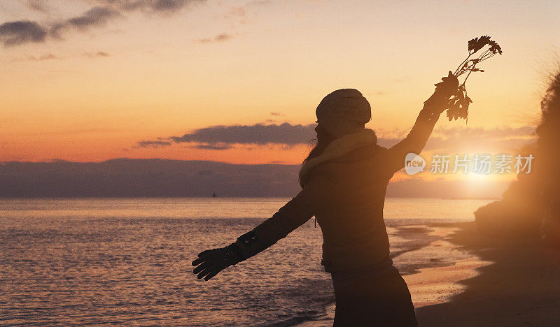 日落时分，愤怒的女人在海滩上向大海抛花