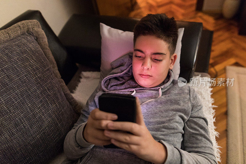 青少年躺在沙发上用手机和朋友聊天，社交网络