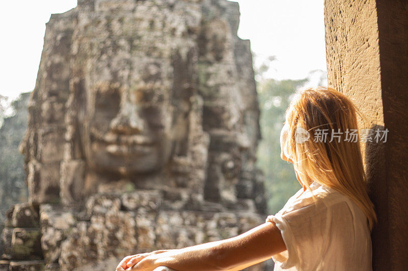 年轻女子凝视着柬埔寨古老的寺庙巴戎寺，吴哥窟建筑群