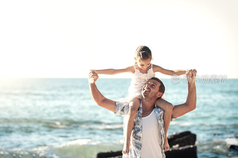 爸爸和女儿在海滩上玩得很开心。在夏天一起在户外玩耍