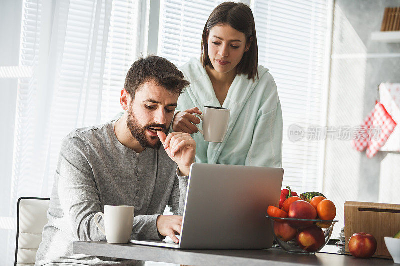 穿着睡衣在家里用笔记本电脑的男人和女人