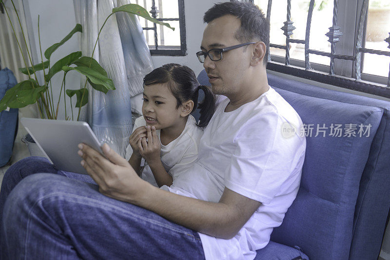 马来西亚父亲和女儿在家里使用平板电脑