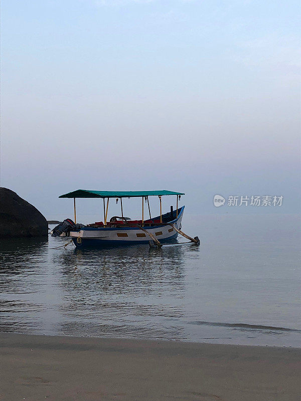 图片中的游船停泊在果阿海岸，准备清晨日出海豚观察巡航，果阿海滩，印度