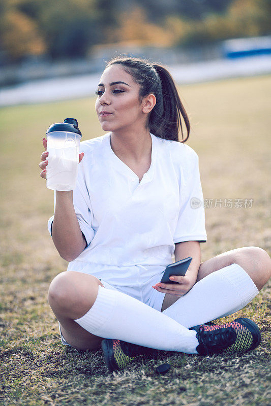 可爱的女足球运动员运动后喝水