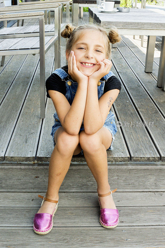 一个美丽的小女孩坐在木台阶上的肖像