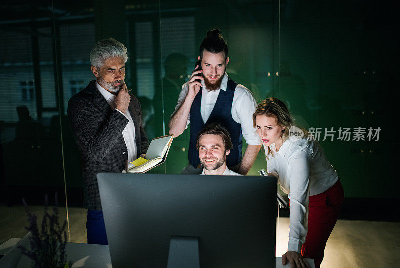 一群商务人士晚上在办公室里使用电脑。