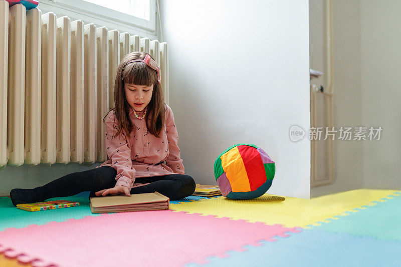 女孩独自坐在地板上，打开一本书