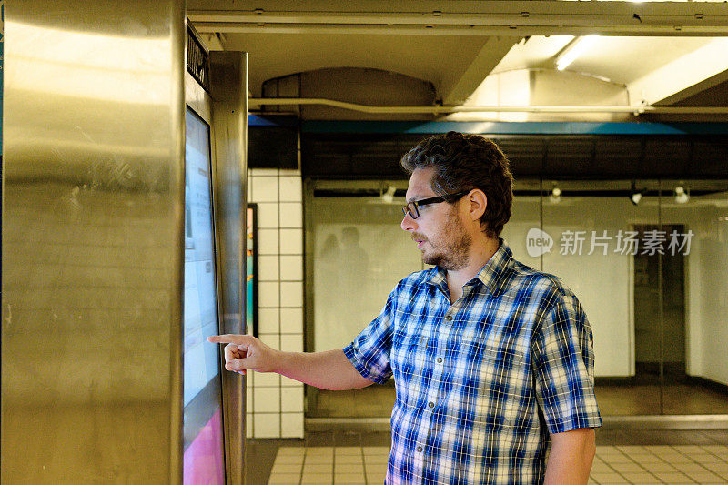 游客在看带有地铁时刻表的数字信息标牌