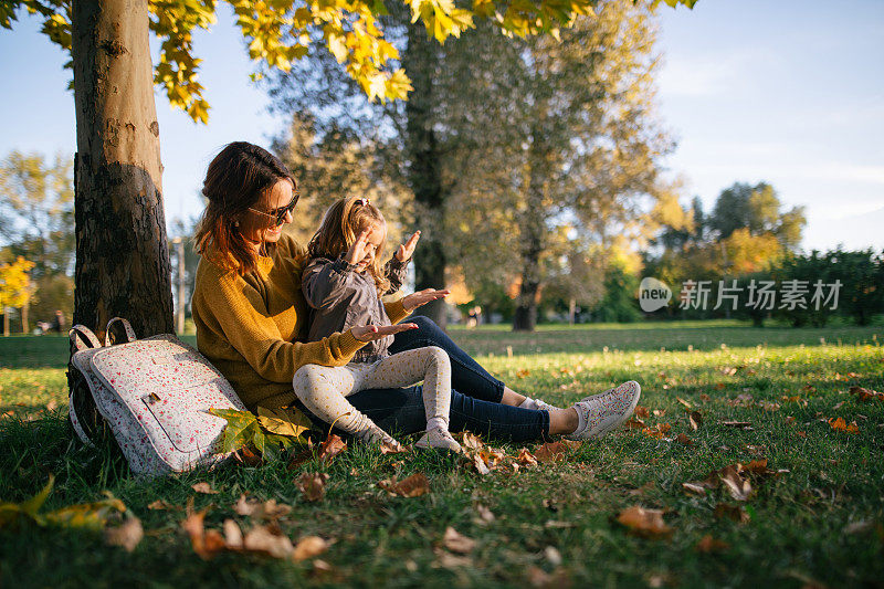 美丽的母亲和女儿在草地上唱歌和鼓掌