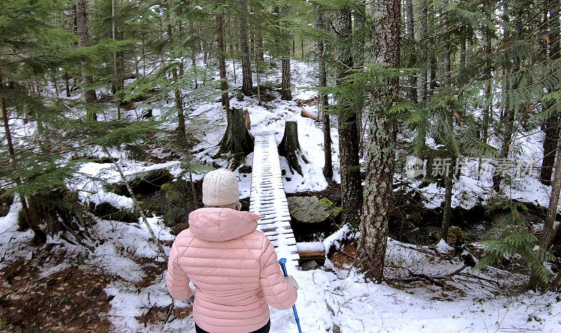 女性徒步旅行者接近积雪覆盖的木板路