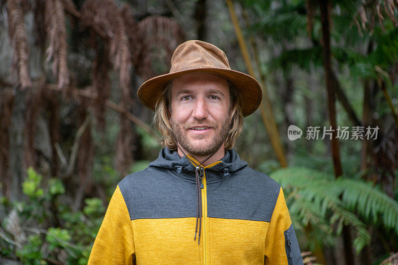 一个年轻人的肖像站在茂盛的树叶在雨林