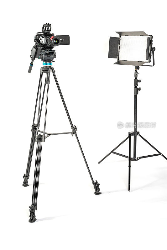 专业的电影摄像机在一个相机三脚架和专业的照明灯具在白色的工作室背景
