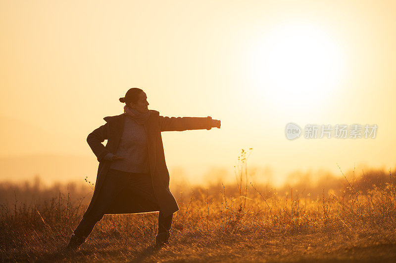 回归自然。日出时分，年轻女子在清晨练习太极。在大自然中做放松练习的快乐女孩的WS。