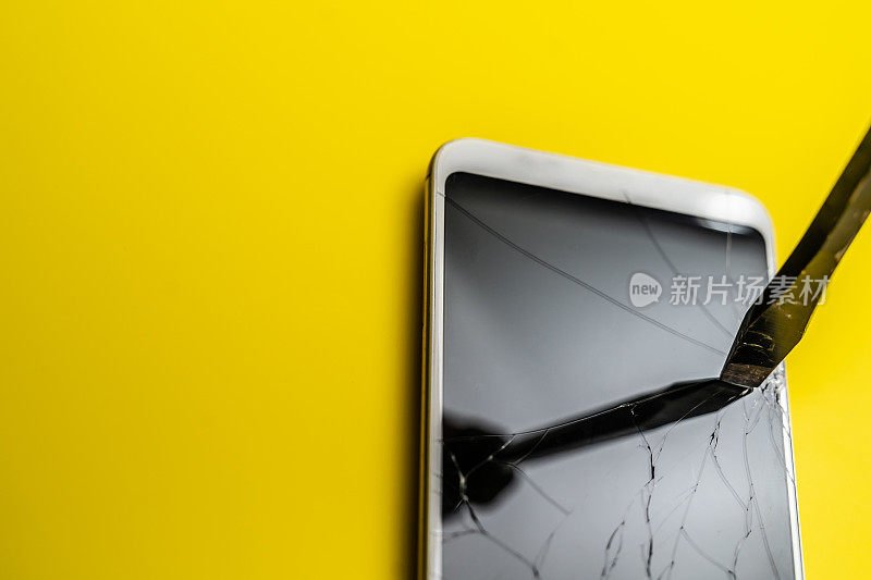 螺丝刀损坏智能手机屏幕，黄色背景