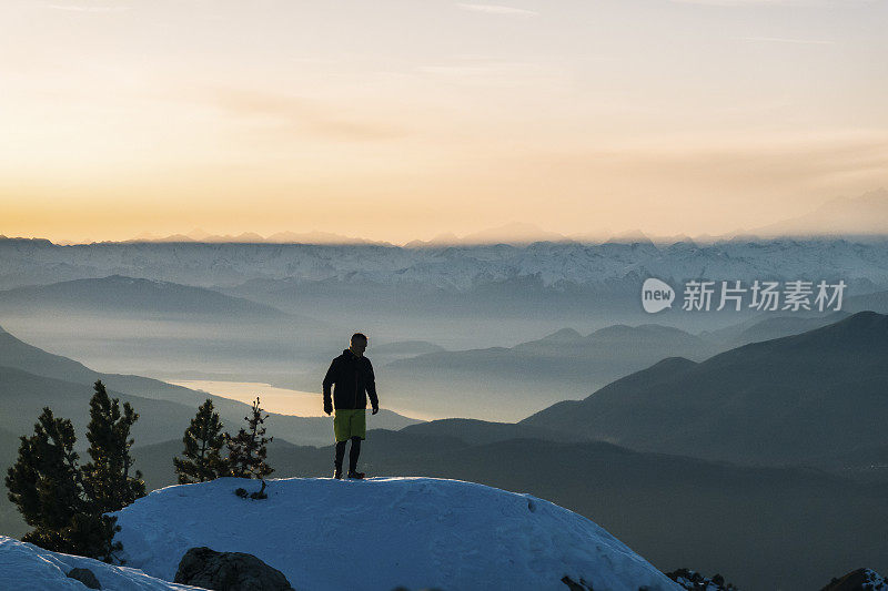 黎明时分，一名徒步运动员爬上雪山的山脊