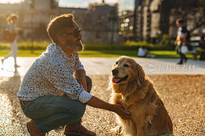 成熟的男人带着金毛猎犬在城市里散步