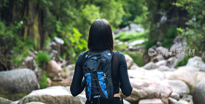 年轻女子背着背包在山里户外旅行