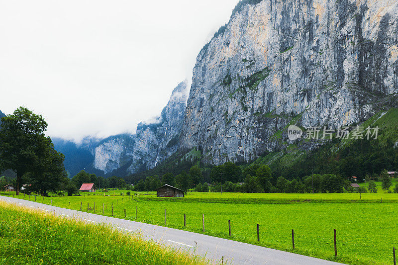 风景优美的道路周围的山脉，瀑布和古老的房子在瑞士