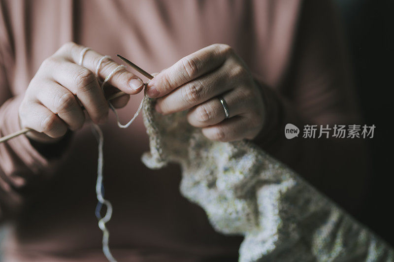 一个亚洲华人中年妇女在客厅编织在她的空闲时间休闲活动