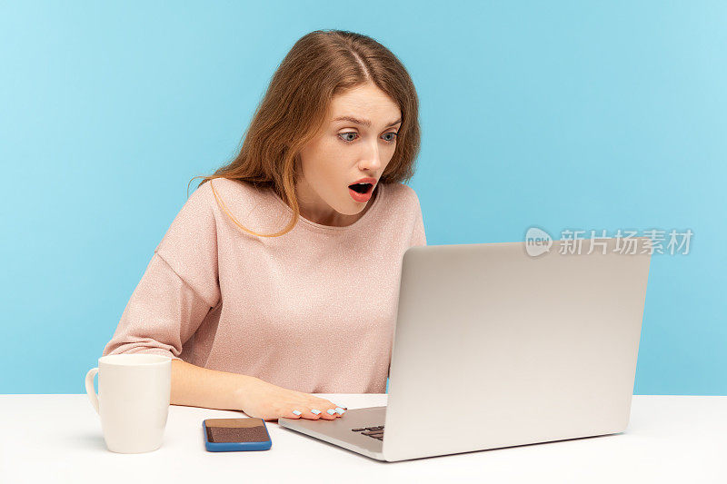 哇,令人难以置信!年轻女子用震惊的表情看着笔记本电脑屏幕与张大的嘴，在视频通话