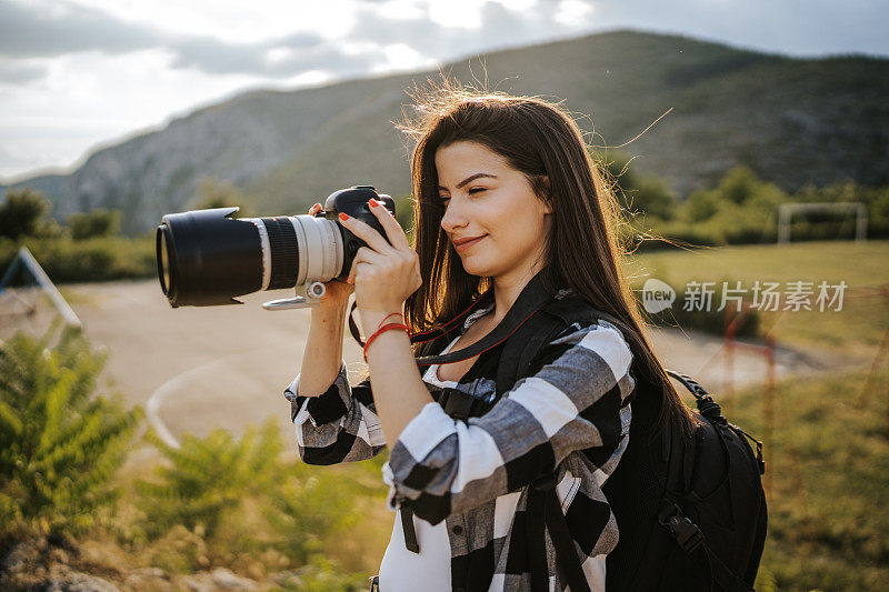 年轻的女摄影师在大自然中拍照