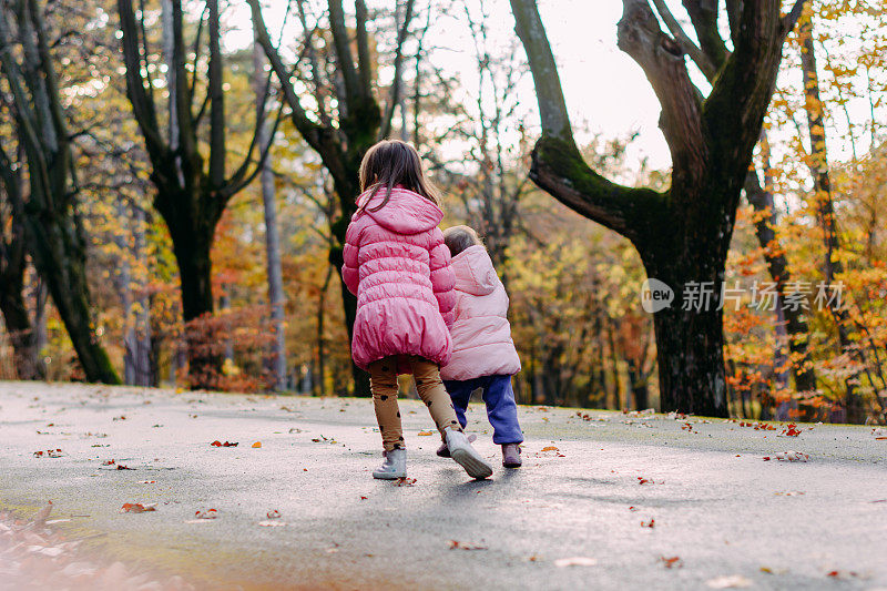 两个孩子在秋天公园里跑步