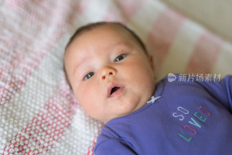 女婴躺在条纹毯子上