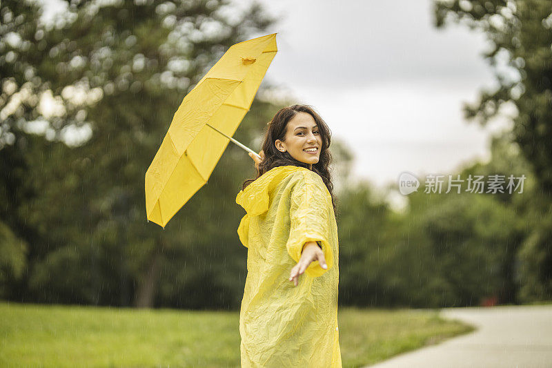 拿着黄伞，穿着黄雨衣，享受着雨的女人