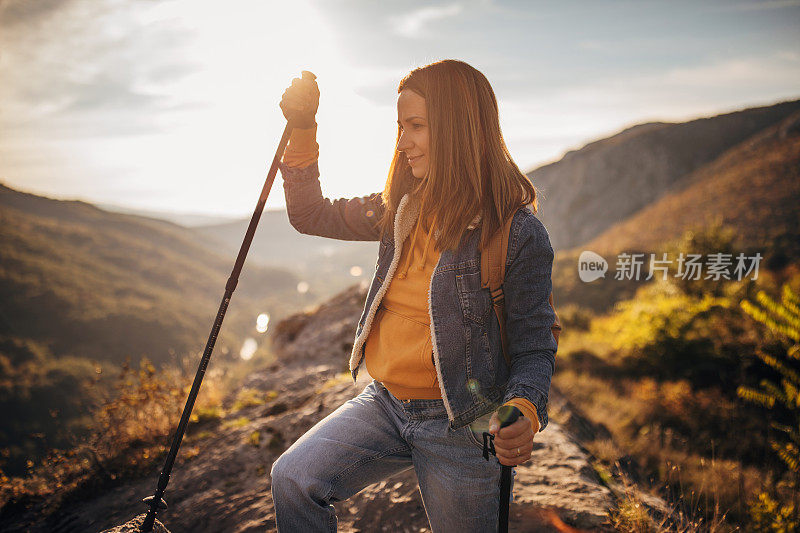 一个漂亮的年轻女子背着背包在山里徒步旅行