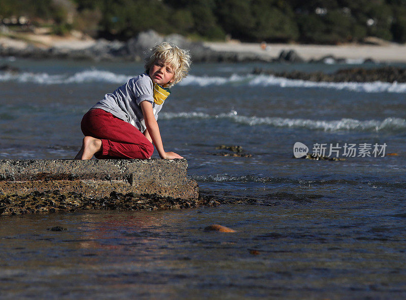 一个在海滩上寻宝的小男孩。