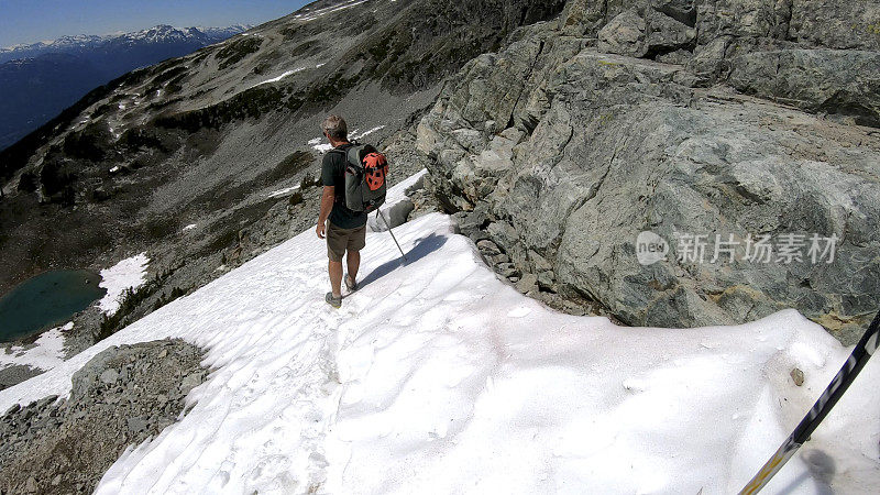 徒步旅行者沿着积雪的山坡跑下去