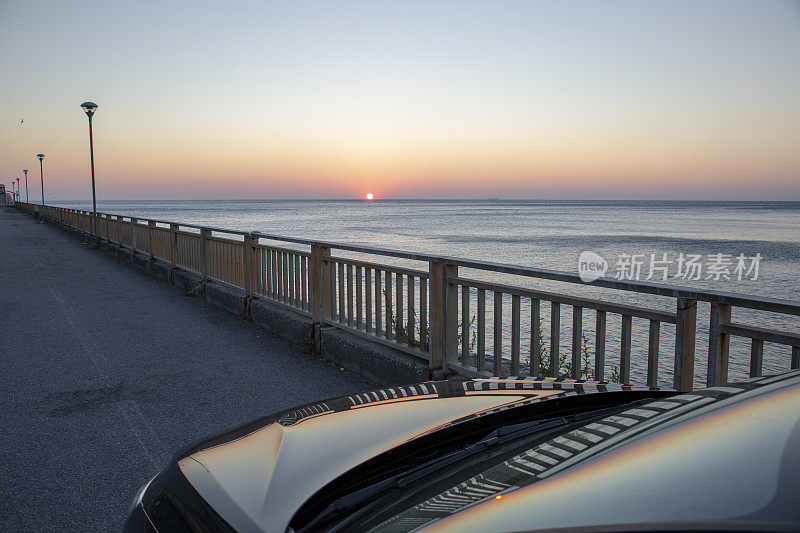 日出时分，汽车坐在海岸码头上的风景