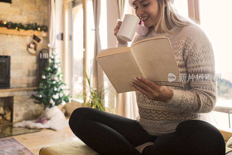 年轻女子在圣诞节早上喝茶和看书