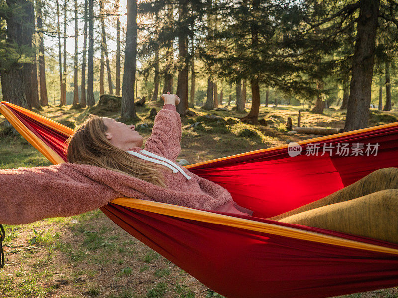 光着脚的女人在森林里的吊床上休息