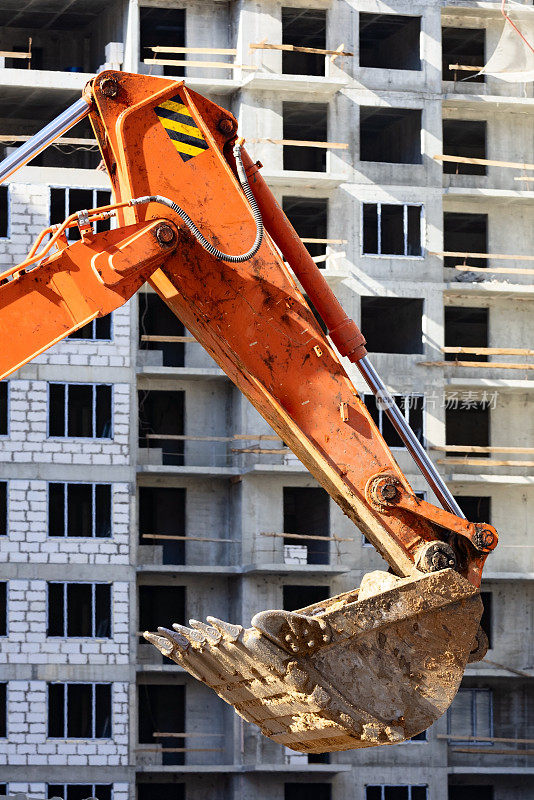 挖掘机铲斗靠墙施工现场的住宅楼