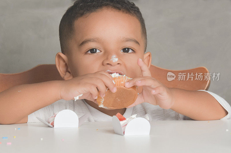 一个小男孩在吃纸杯蛋糕