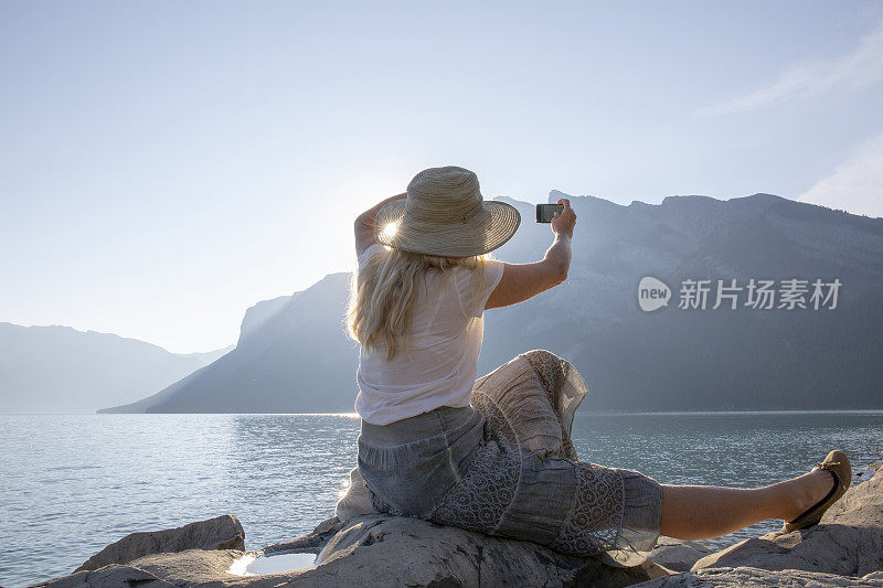 女人在山湖边休息，拍照