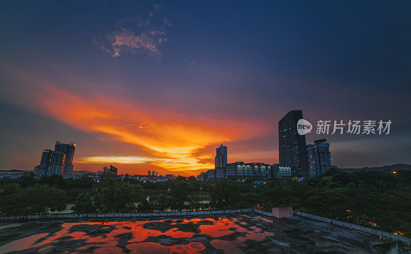 在剪影中傍晚日落与戏剧性的天空城市景观反射在屋顶空的停车场