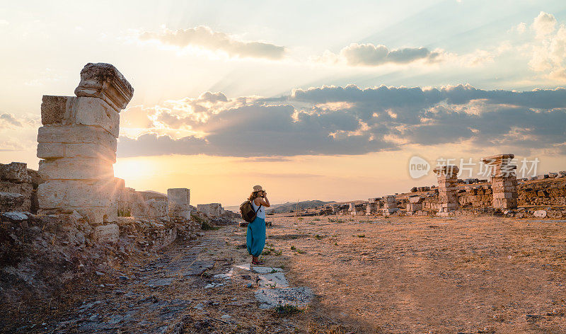 旅行者旅行者摄影师女孩正在拍摄古老的废墟上的拉库斯日落，Pamukkale