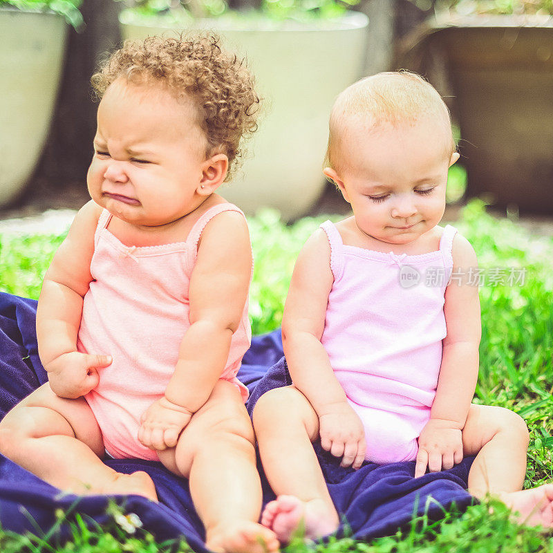 两个小婴儿一起坐在户外，女性的友谊或竞争