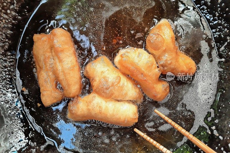 用滚烫的食用油煎炸油条。