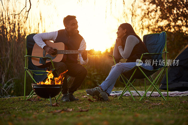 在一次露营旅行中，一个年轻人弹吉他为他的女朋友唱小夜曲