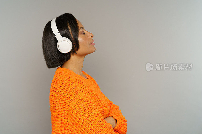 年轻心满意足的美国黑人女性闭着眼睛戴着耳机听音乐或播客