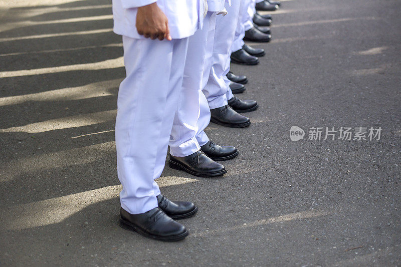 在白色服装和黑色鞋子的游行队伍中排队