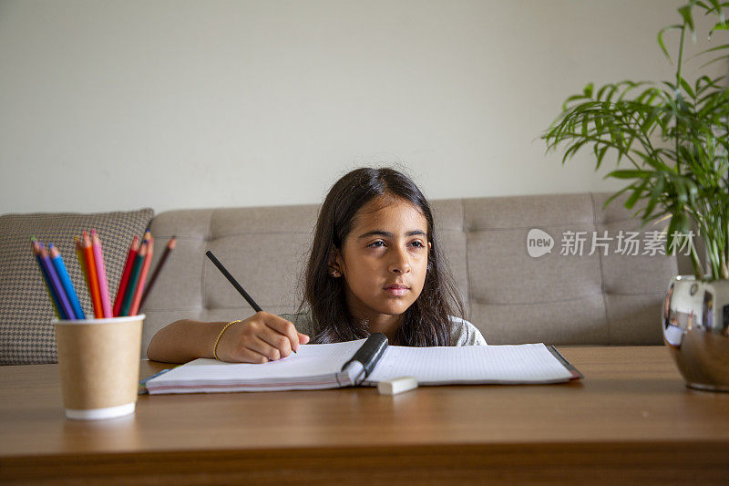 一个小女孩在家里的书桌上做作业