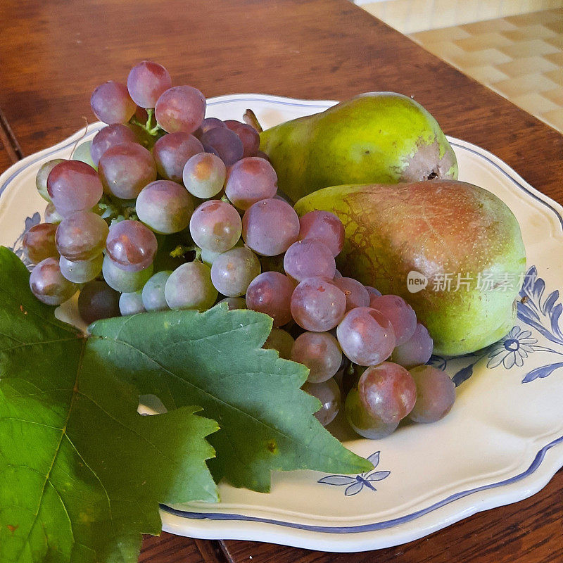 葡萄和梨放在瓷盘里