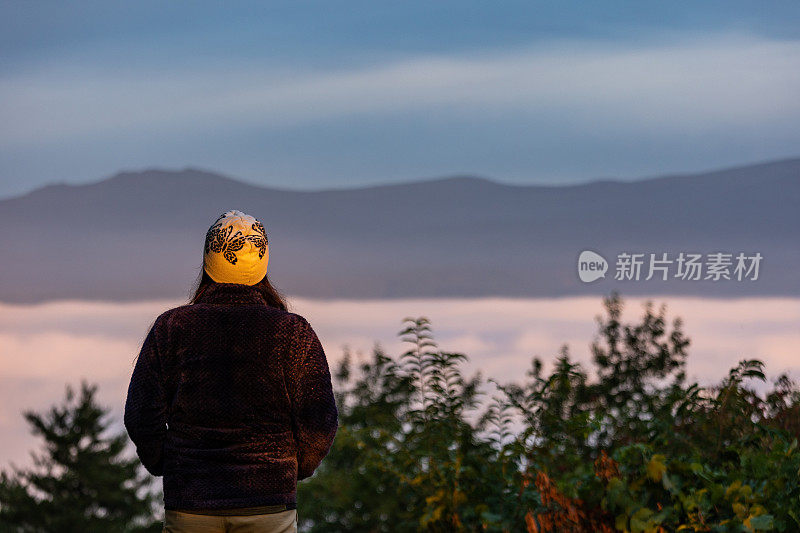 一个女人在云海上欣赏日出的山景