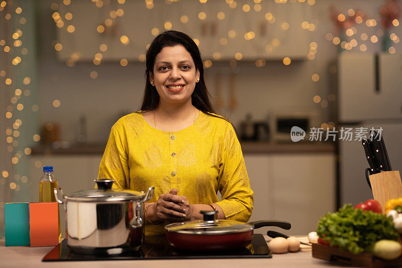 印度妇女在厨房做饭时享受的画像。库存图片